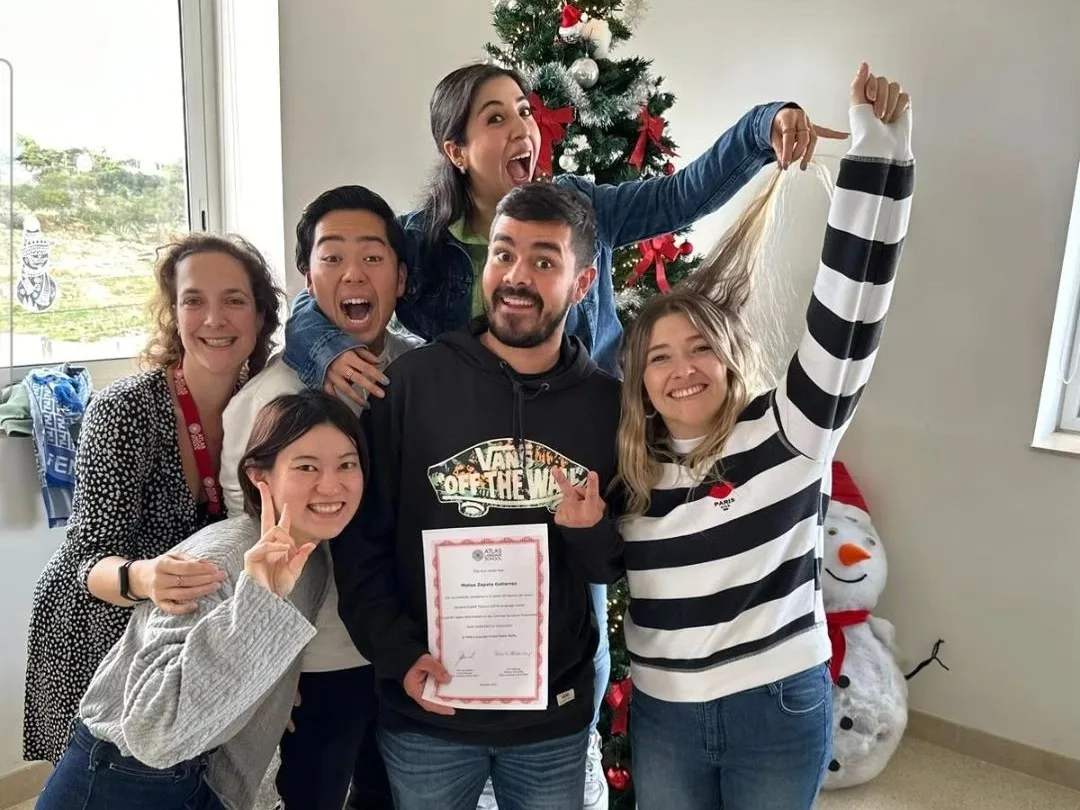 Students celebrating by a Christmas tree, one holding up his course certificate