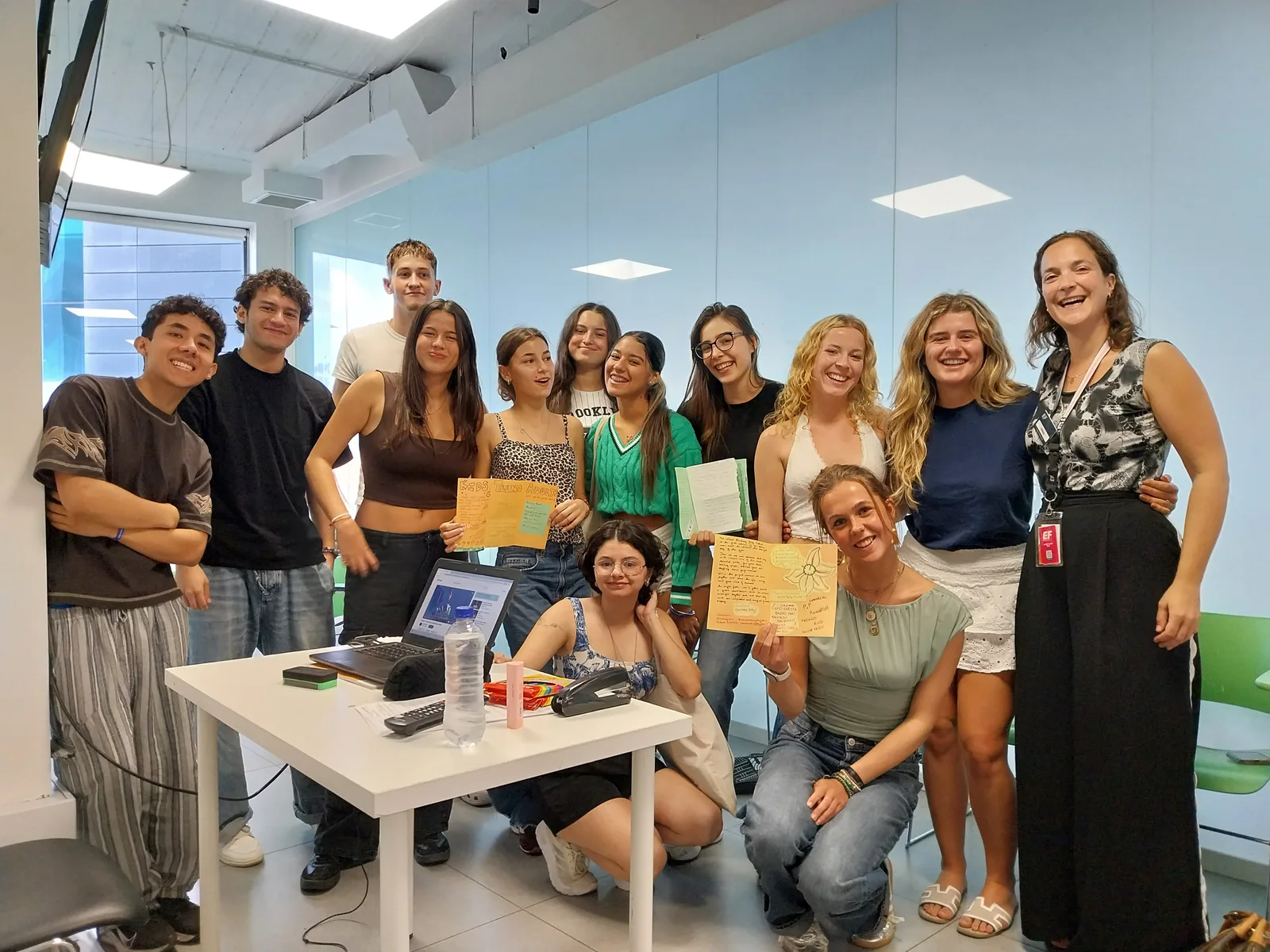 A smiling group of students with their teacher Amber, on the right, in a bright classroom