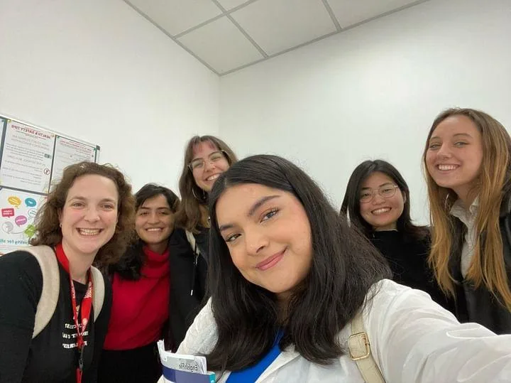 A smiling selfie of a student with her classmates and teacher