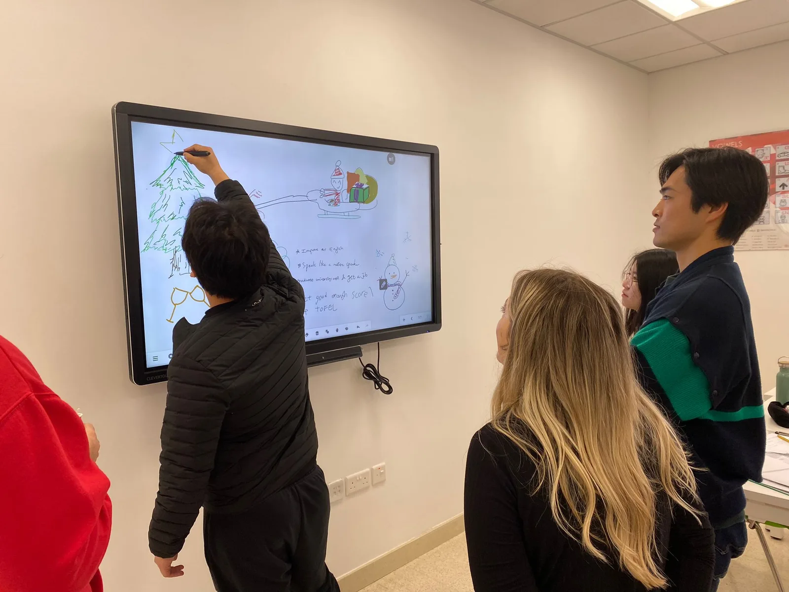 A student drawing on the interactive whiteboard while classmates watch